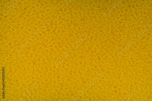 The rough texture of yellow plastic sponge scrubber with holes for background