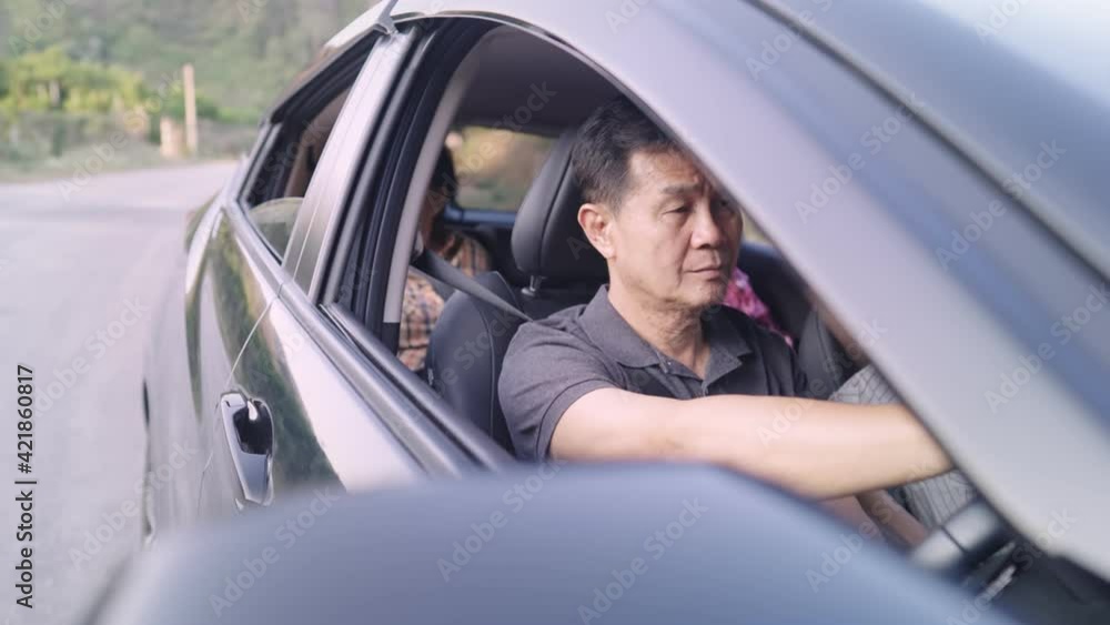 Asian family having a happy moment on holiday together. auntie having a fun conversation with toothy smiling face on back seat while father intently driving for family's safety, family on travelling Asian family having a happy moment on holiday together. auntie having a fun conversation with toothy smiling face on back seat while father intently driving for family's safety, family on travelling