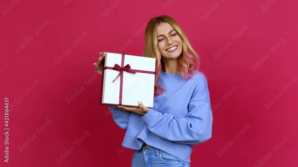 Young blonde woman happy and holding a gift over isolated background Young blonde woman happy and holding a gift over isolated background