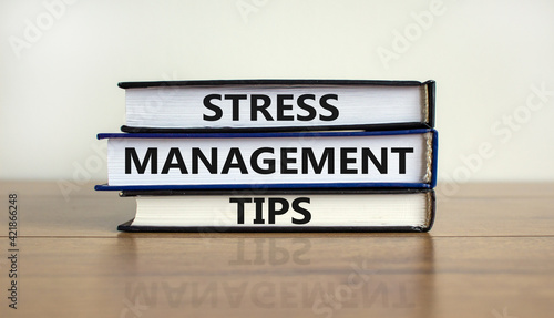 Stress management tips symbol. Books with words 'Stress management tips'. Beautiful wooden table, white background. Psychological, business and stress management tips concept. Copy space.