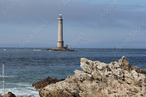 beautiful landscape at the french coast in normandy with the lighthouse of cap de la hague in the sea and a rock in front in summer