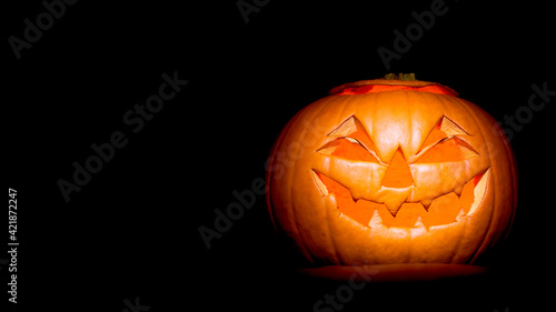 Halloween jack-o-lantern (will-o-the-wisp) made from a pumpkin on black background with copy space for use as a header or banner © Damian Pawlos