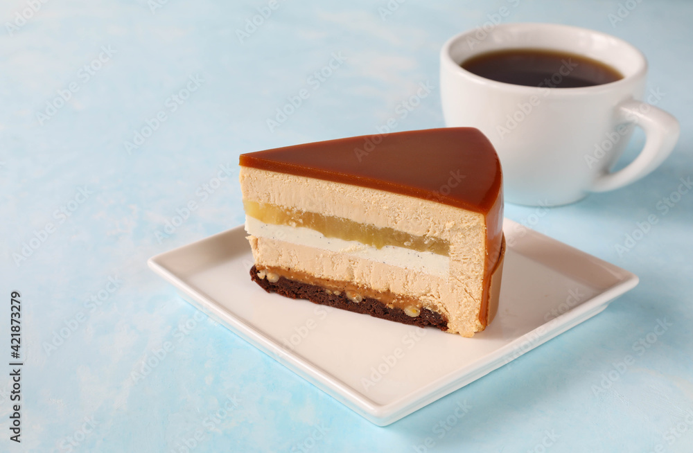 A piece of cake on a square plate with a cup of tea A piece of cake on a square plate with a cup of tea