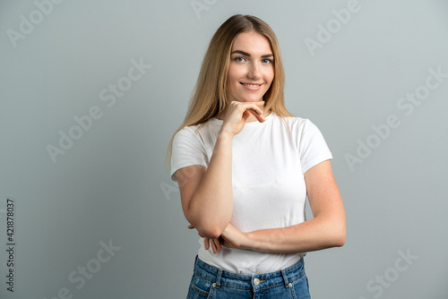 Pretty female with blonde hair, dressed casually, looking at the camera, being happy. Shot studio of a beautiful woman, isolated from a blank studio wall.