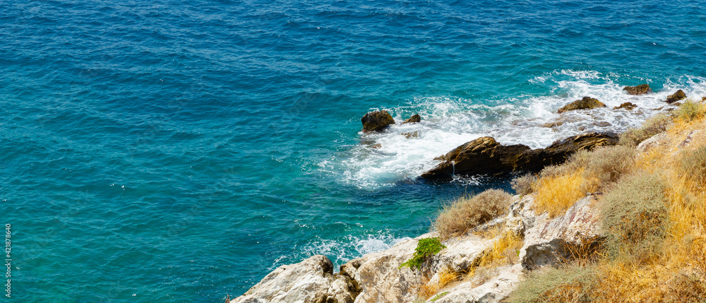 Horizontal view of the turquoise waters of the sea. Wild clifs in front of turquoise water. Summer vacation by the sea