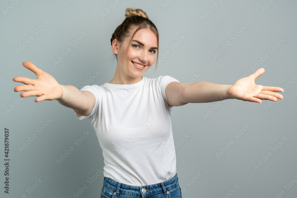 Beautiful young woman standing over gray wall looking at the camera smiling with open arms for hug. Cheerful expression embracing happiness. Beautiful young woman standing over gray wall looking at the camera smiling with open arms for hug. Cheerful expression embracing happiness.