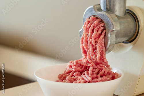 Fototapet mince the meat with an electric meat mincer