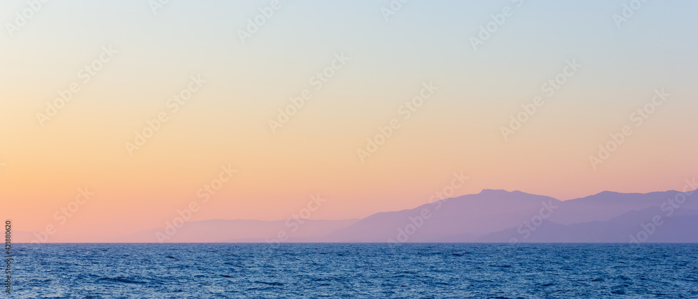 Seascape with fog and mountains. Seascape at sunset. View from the sea to the mountains in the haze. Dramatic scenes and the beauty of nature
