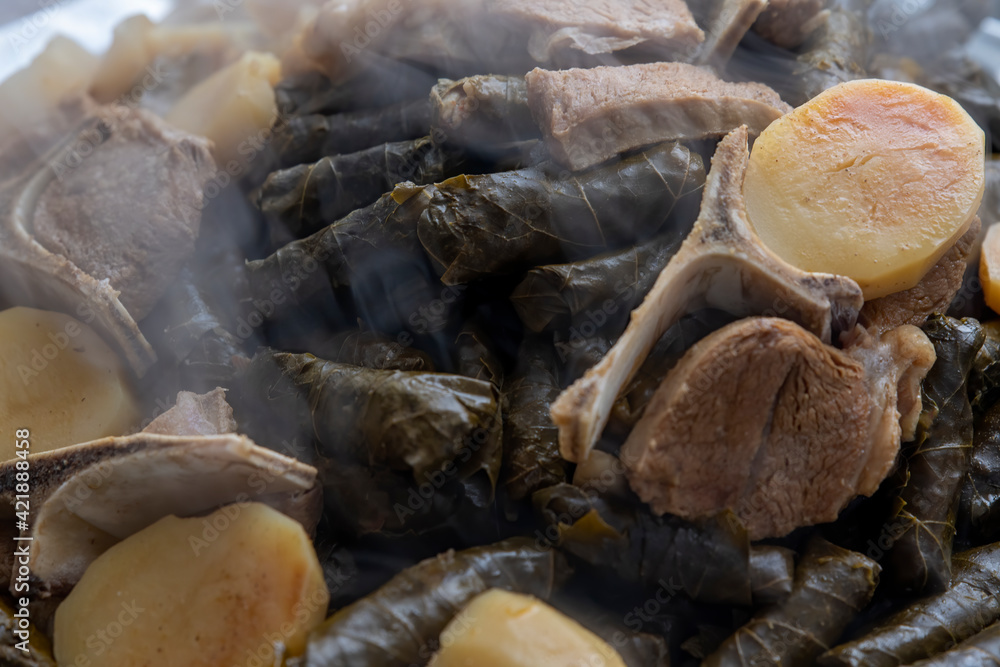 Top view, of a hot just finished cooked Plate of stuffed grape leaves called Dolma , made from vines with rice, meat and spices. Top view, of a hot just finished cooked Plate of stuffed grape leaves called Dolma , made from vines with rice, meat and spices.
