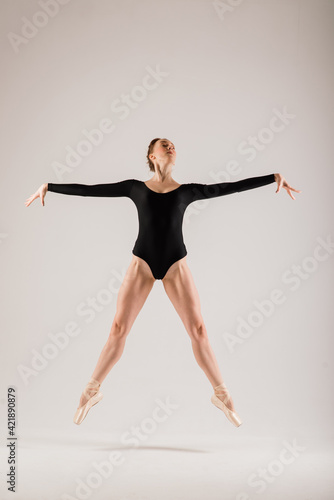 Modern style ballet dancer posing on studio background