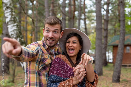 A smiling young couple is hugging and enjoying autumn colors in the forest