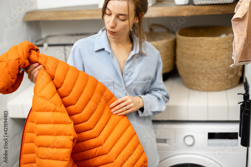 Young housewife looks on a down jacket before washing