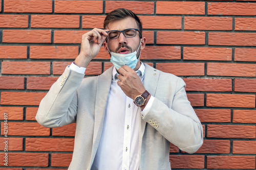 Portrait of the young man standing in front of the brick wall with a face mask.