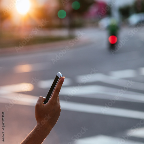 Hand of girl pedestrian with smarthphone crossing road.