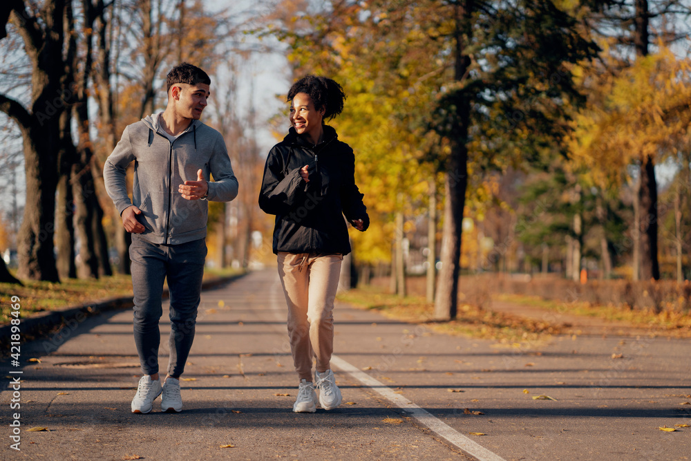 Obraz premium sports couple in the park in the morning. Heart training cardio system in the fresh air, useful for blood vessels. They are engaged in long-distance running. Comfortable sportswear.