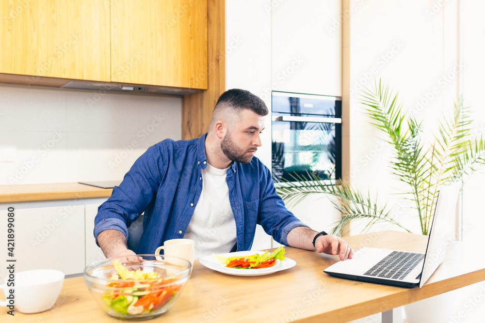 Young male businessman having breakfast at home, and doing business, on a notebook Young male businessman having breakfast at home, and doing business, on a notebook