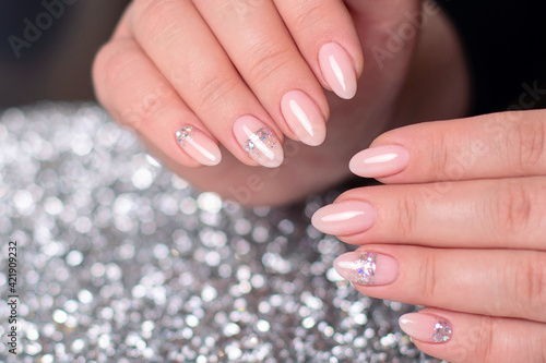 Beautiful female hands with romantic manicure nails, nude gel polish with silver glitter