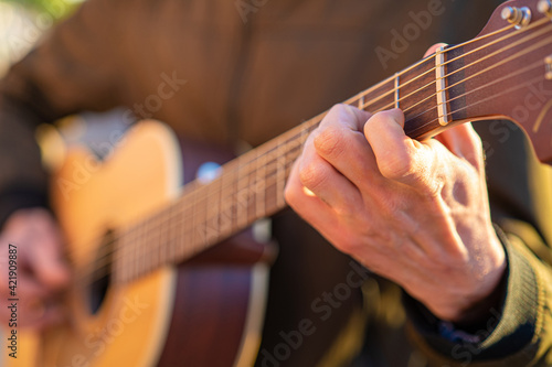Mano de un guitarrista poniendo un acorde en una guitarra acústica de madera