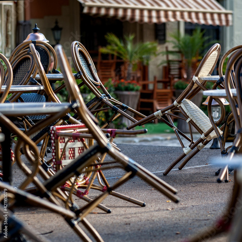 An empty summer outdoor area of a restaurant or cafe in a historic downtown is closed during lockdown. Tables and chairs without visitors. Challenging times business in HoReCa during a pandemic. photo