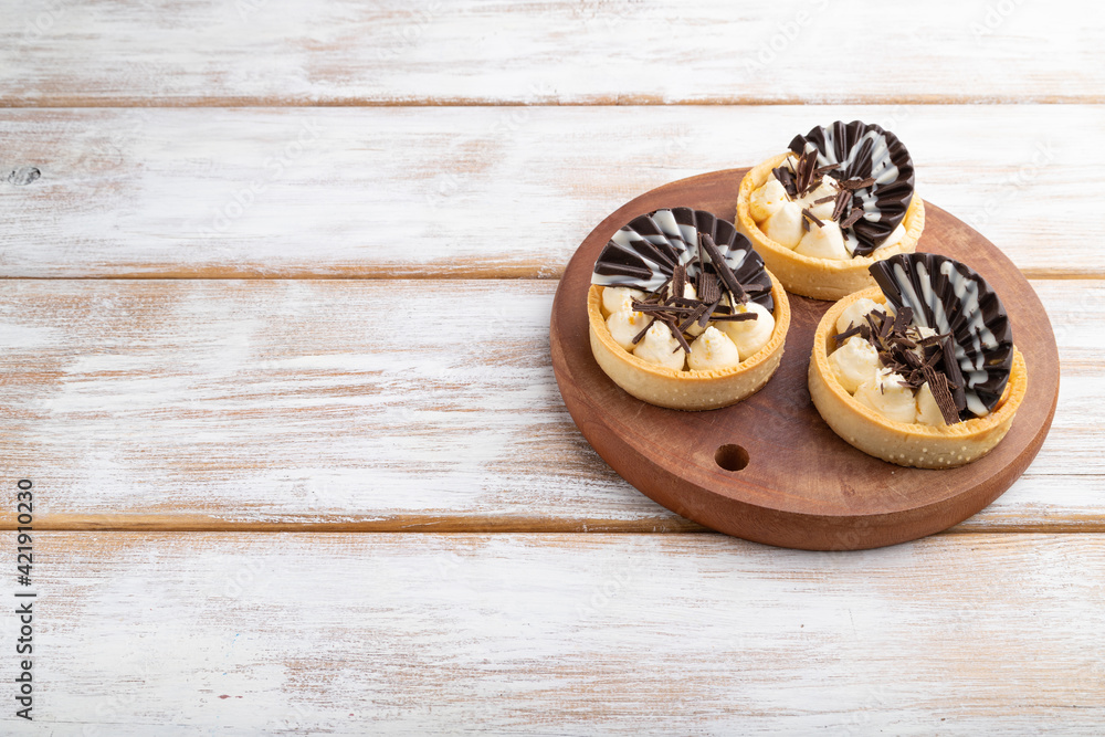 Sweet tartlets with chocolate and cheese cream on a white wooden background. side view, copy space.