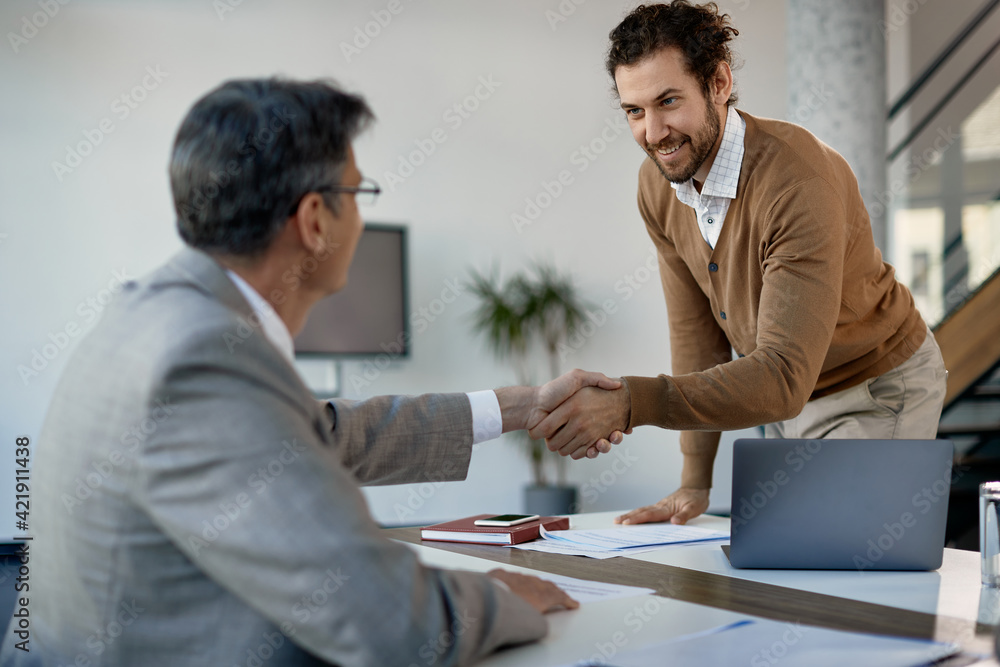 Young happy businessman handshaking with executive manager on meeting at corporate office.