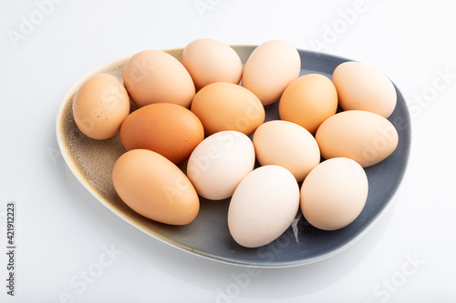 Pile of colored chicken eggs on plate isolated on white background. side view.