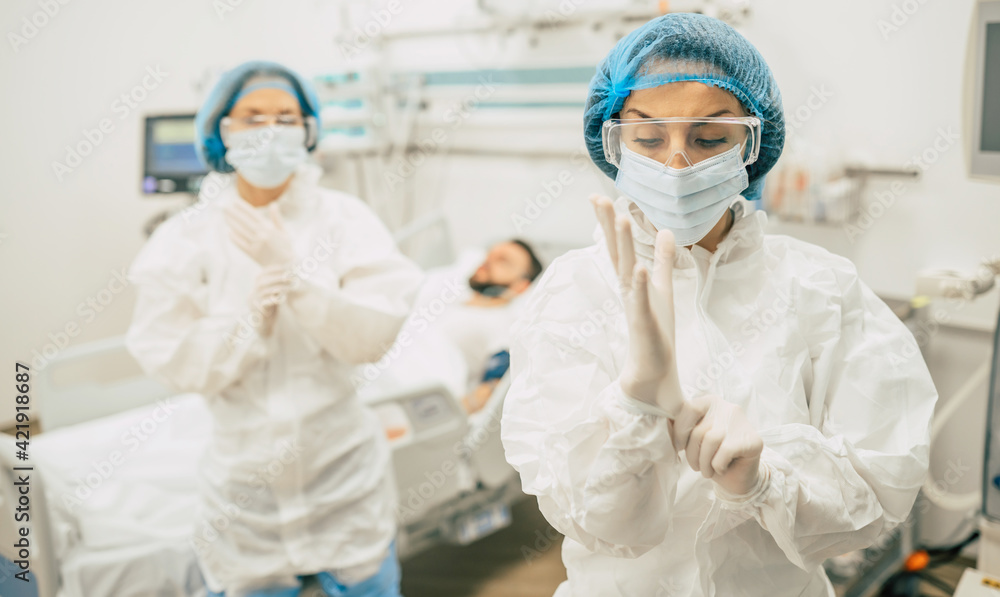 Naklejka premium Coronavirus covid-19 infected patient in a quarantine ward at the hospital with doctors in protective suits while they making disease treatment of him