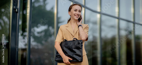 Closeup Portrait of an businesswoman standing outside office building and speaking mobile phone