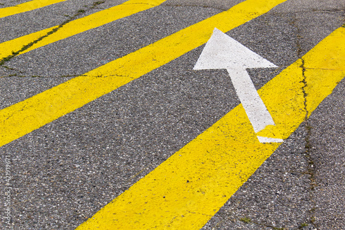 Grey asphalt highway drive road with yellow lines and white arrow 