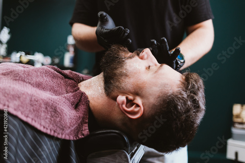 Shaving and beard care in barbershop, hairdresser applying cosmetic gel