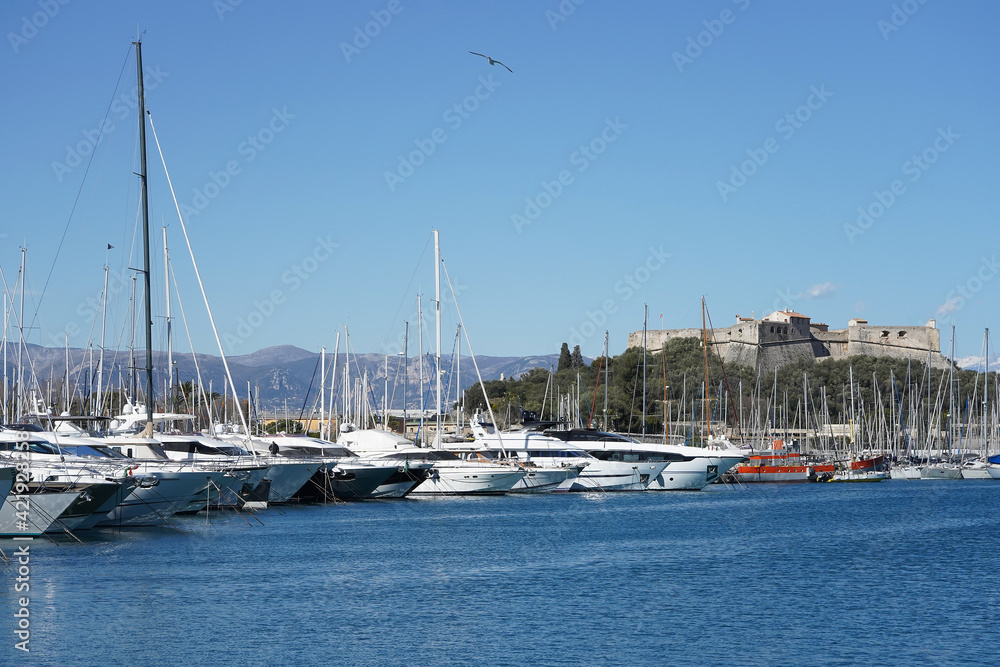 View of the yachts in the port on the Mediterranean Sea and Fort Carré in the distance. Antibes, France.