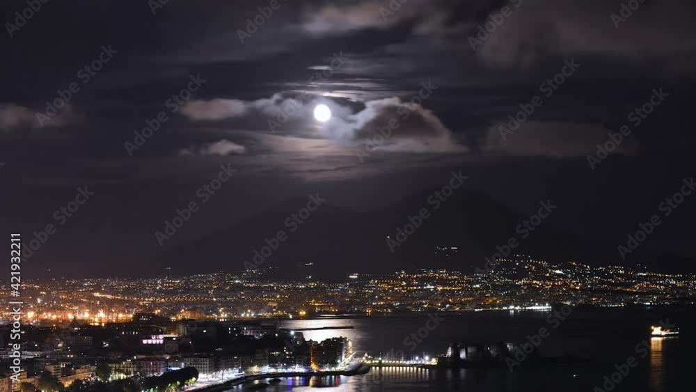 Video del golfo di Napoli di notte in Timelapse con la Luna che sorge dietro il Vesuvio in mezzo alle nuvole e le colorate luci della città metropolitana e il riflesso argenteo della Luna sul mare Video del golfo di Napoli di notte in Timelapse con la Luna che sorge dietro il Vesuvio in mezzo alle nuvole e le colorate luci della città metropolitana e il riflesso argenteo della Luna sul mare