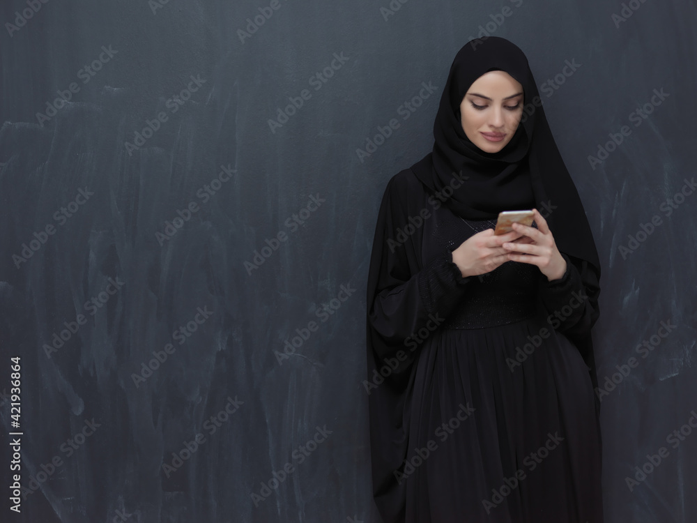 Young muslim businesswoman in traditional clothes or abaya using smartphone Young muslim businesswoman in traditional clothes or abaya using smartphone
