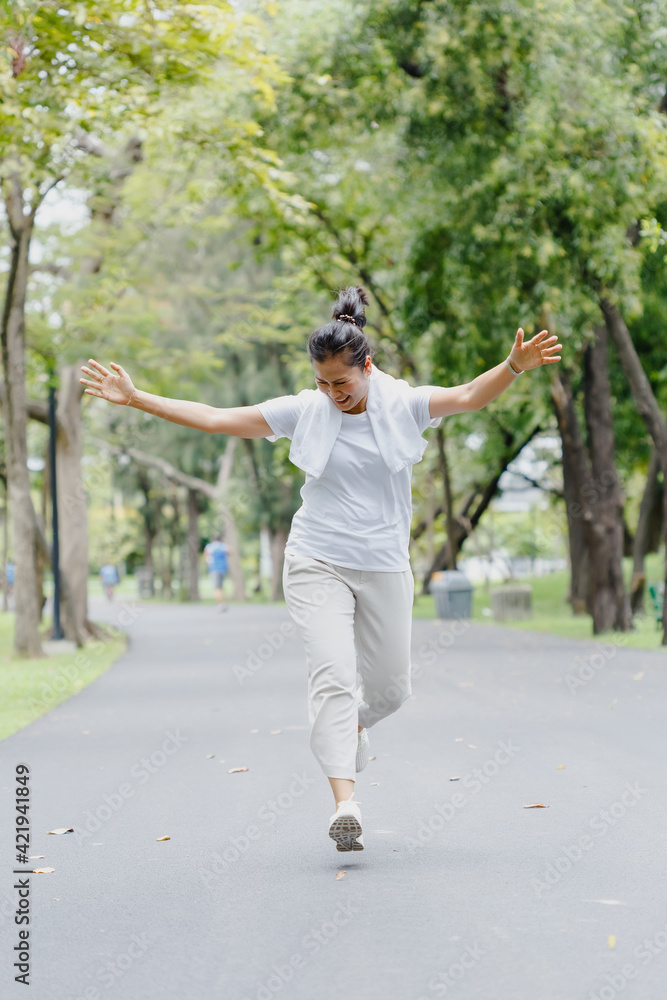 asian woman senior sportswear cheerful running and arms outstretched. joyful exercise in garden. happy mature healthy lifestyle.