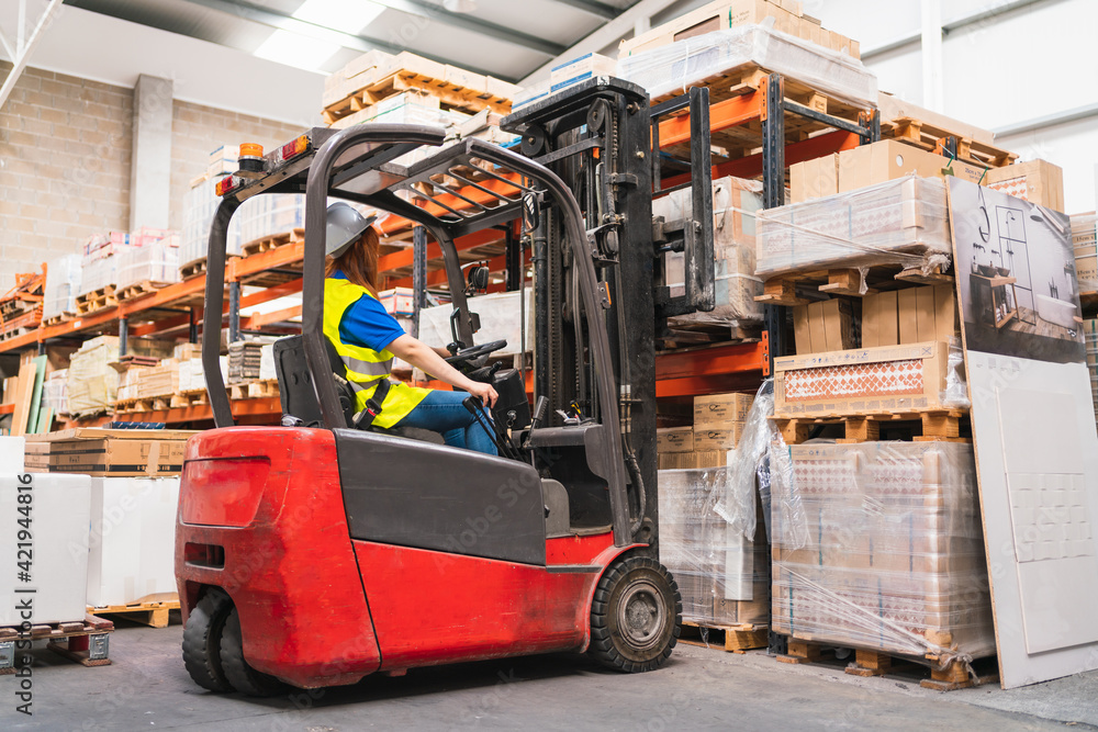 young woman worker using a forklift in a warehouse
