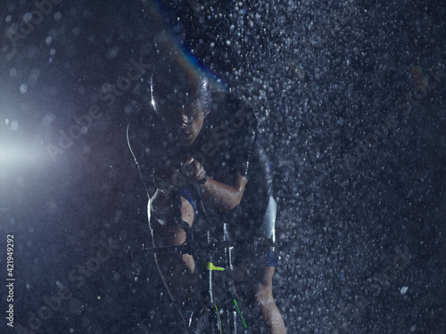 triathlon athlete riding bike on rainy night