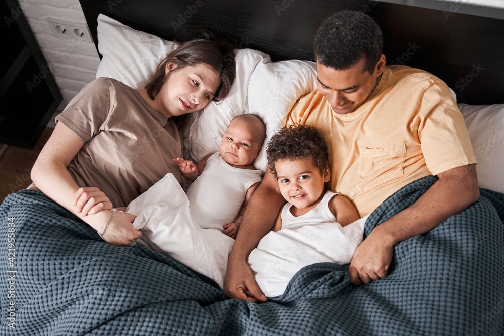 Mother, father and their kids hugging and relaxing at the bedroom Mother, father and their kids hugging and relaxing at the bedroom