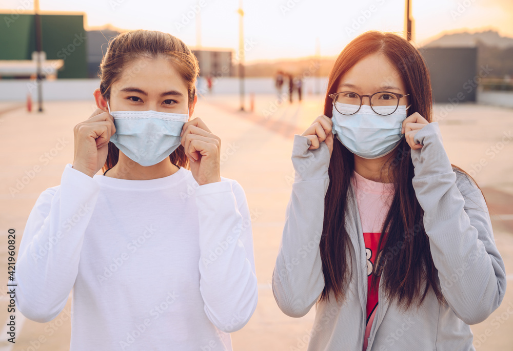 Two Asian women wearing surgical mask in covid-19 pandemic outbreak. New normal lifestyle, should wear a mask to keep your nose and mouth covered when in public.