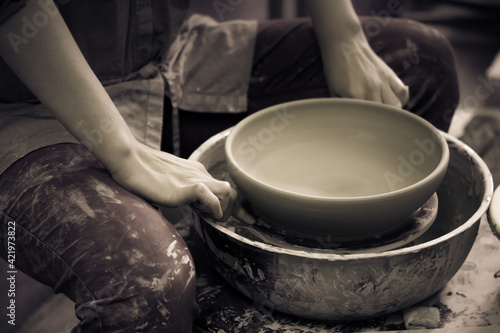 Potter holds round clay plate in his hands.