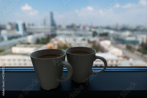 coffee mugs standing on the windowsill against the backdrop of a beautiful city