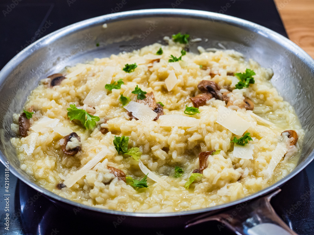 Risotto with white mushrooms and parmesan cooking in frying pan
Risotto with white mushrooms and parmesan cooking in frying pan