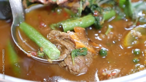 Close Up Footage of Hot and Spicy Beef Clear Soup Curry ( Kang Paa or Jungle Curry) With Long Curd Beans and Holy Basil Leaves, One of the Delicious Homemade Dish In Thailand photo