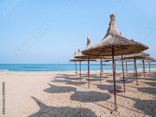 Summer landscape with straw umbrellas on the beach in Mangalia or Mamaia. Beach at the Black Sea in Romania.