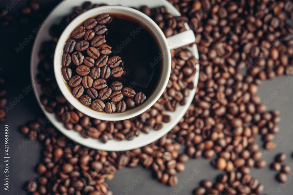 Fototapeta premium coffee beans on a gray background and a hot aromatic drink on a saucer top view