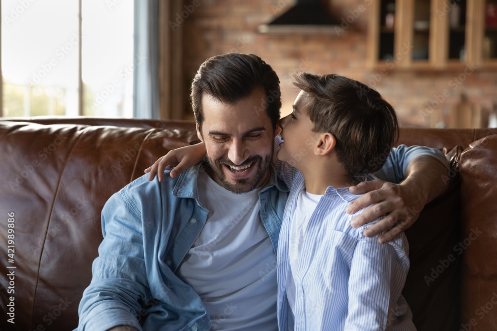 Φωτογραφία Cute little 7s Caucasian boy kid whisper tell secret to excited young father, relaxing together at home
