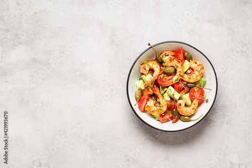 Easy grilled shrimp avocado salad with cherry tomatoes, capers and microgreens. Gray background. Top view. Space for text.