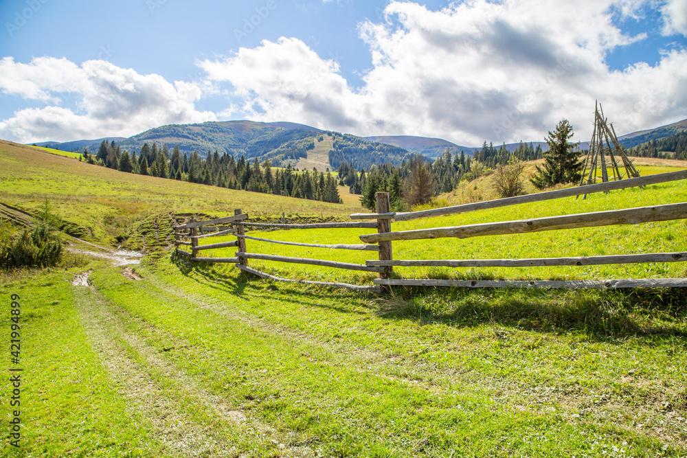 countryside in the mountains on a clear summer day. road near the wooden fence on a background of mountainous terrain.