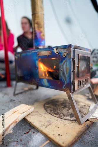 Life in a lavvo tent or tipi in the cold winter. Focus on the hot firestove that heats up the tent. It is extremely cold outside, but warm and nice inside.  photo