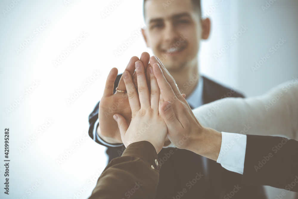 Fototapeta premium Business people group showing teamwork and joining hands or giving five in modern office. Unknown businessman and women making circle with their hands