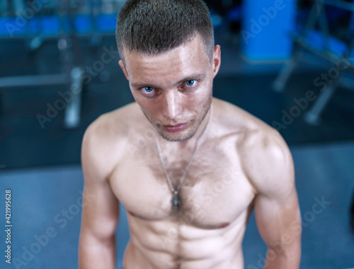 muscular blue-eyed guy with a naked torso posing looking at the camera